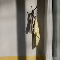 “Yellow and brown checkered towels hanging against a neutral wall with soft shadows for a warm, inviting feel.”