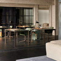 Modern office space with gray concrete walls, sleek wooden desks, and green-accented chairs, featuring a minimalist design.