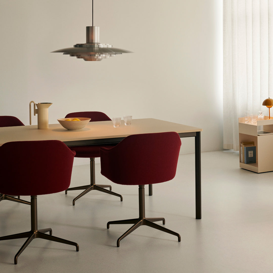 Red velvet chairs and a sleek light fixture complement a minimalist beige and white dining space. Modern design aesthetics.