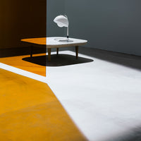 Modern coffee table on a split-color floor featuring warm orange and cool white geometric patterns.