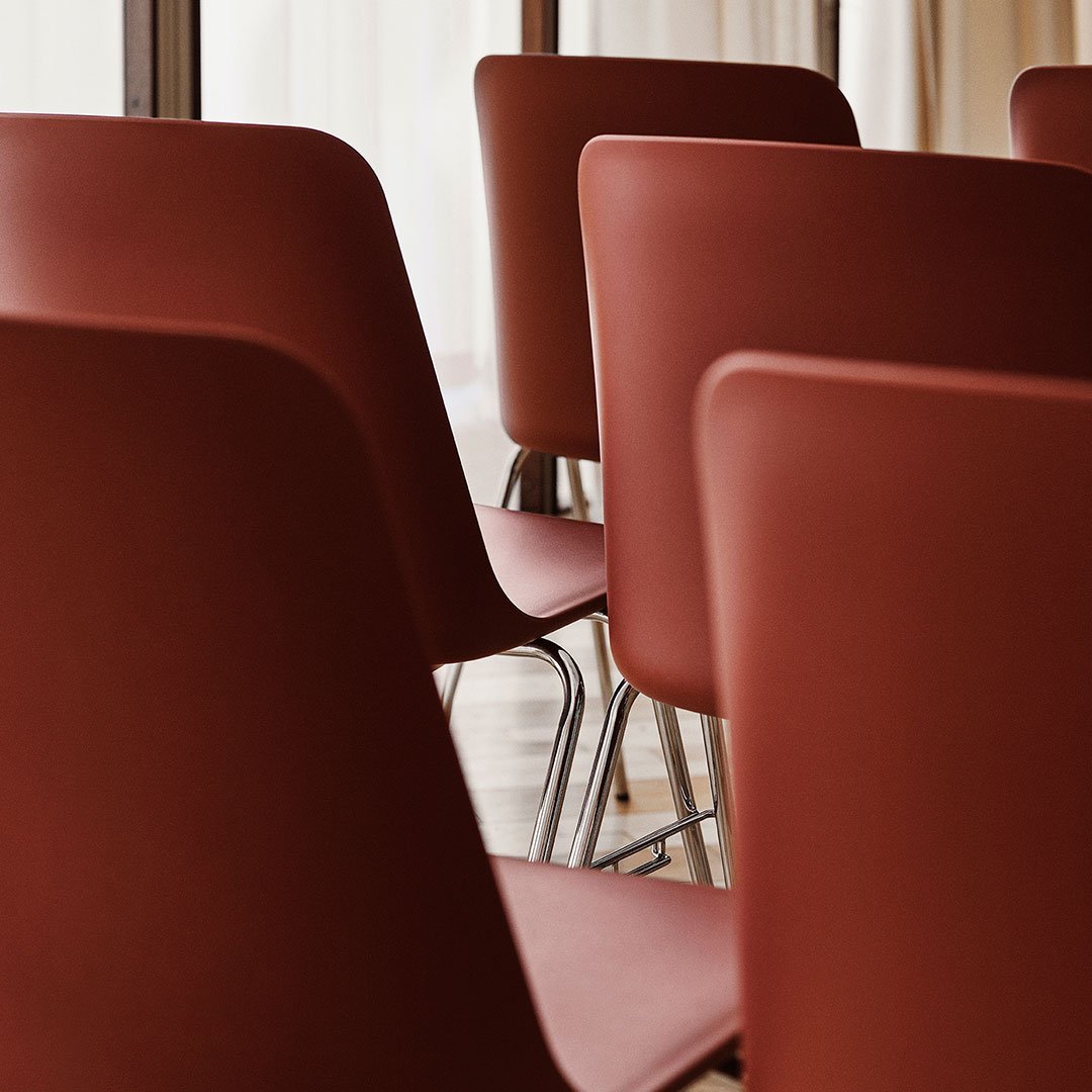 "Close-up of modern chairs featuring a deep rust color and sleek, minimalistic design."