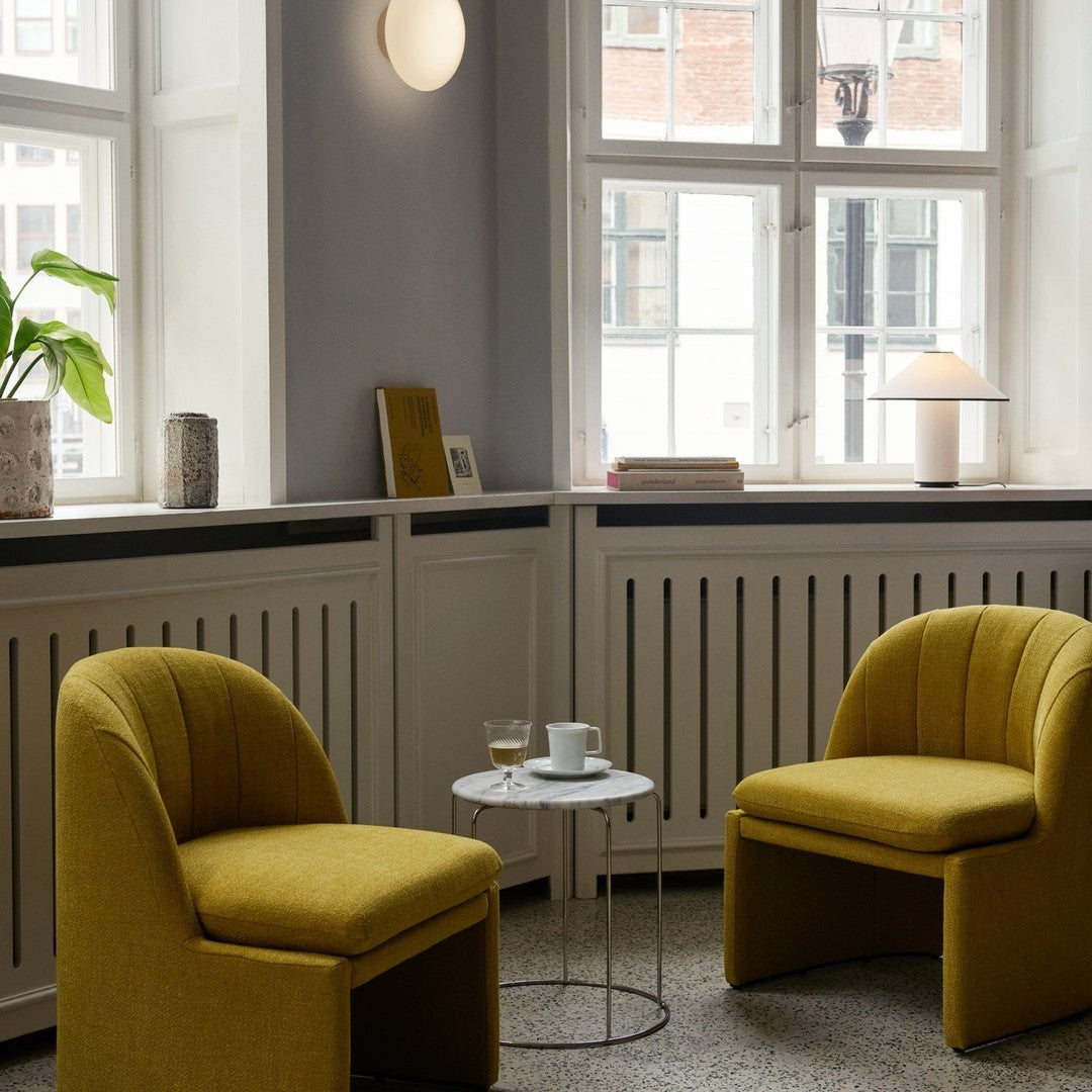 Yellow upholstered chairs with ribbed patterns in a stylish interior featuring light gray walls and marble accents.