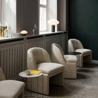 Textured cream chairs against a dark green wall, featuring a marble side table and minimalistic decor.