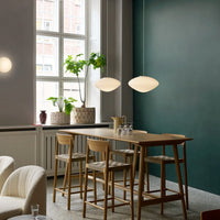 Modern dining area with dark green walls, light wood furniture, and neutral-toned decor accents. Stylish and minimalistic design.