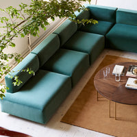 "Teal sectional sofa with a modern design, featuring solid color patterns and clean lines, paired with a round wooden table."