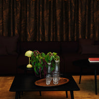 Elegant dark brown curtains with a subtle leaf pattern, paired with a black coffee table and green foliage.