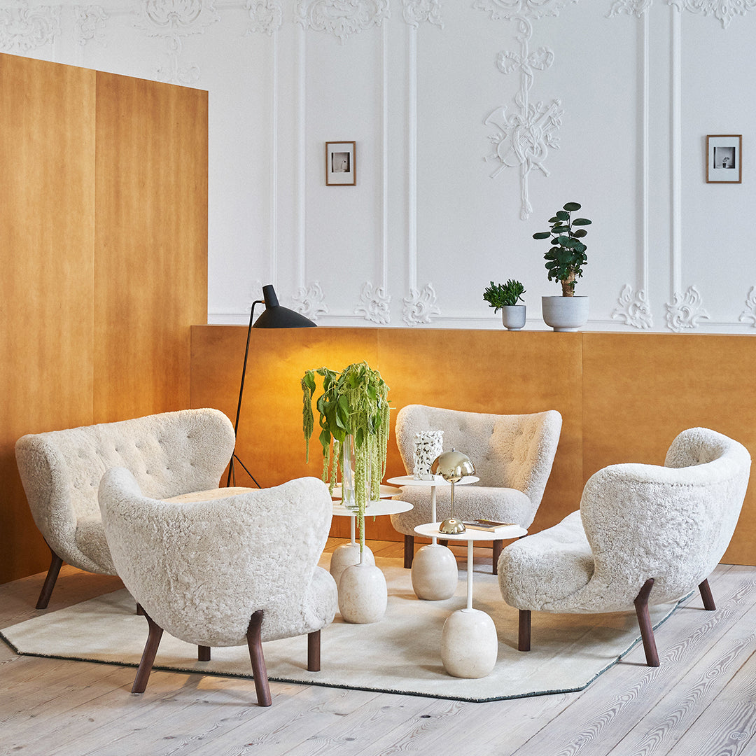 Cream textured chairs with light wood accents, set against warm wooden walls and a soft, neutral rug.