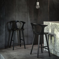 Black bar stools against a textured gray wall and a speckled countertop, creating a modern, minimalist aesthetic.