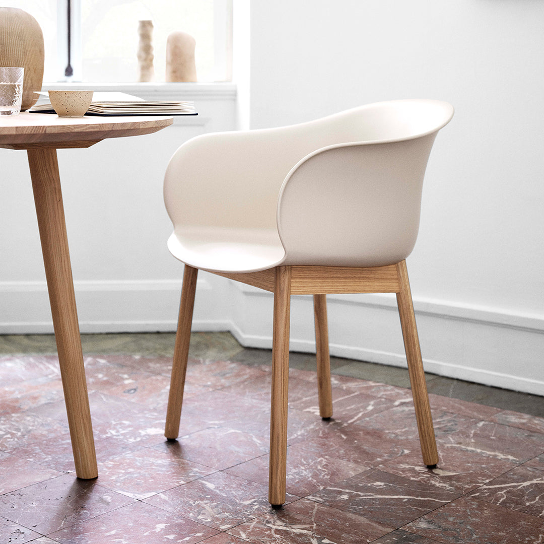 Modern beige chair with smooth curves and a natural wood base, set against a minimalist background.