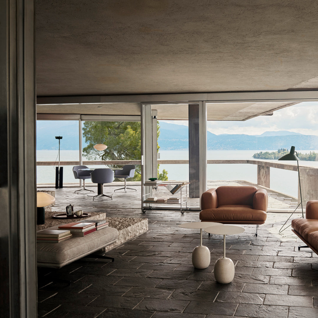 Modern interior featuring earthy tones, sleek furniture, and natural textures with a serene waterfront view.