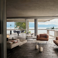 Modern interior featuring earthy tones, sleek furniture, and natural textures with a serene waterfront view.