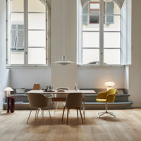 Modern dining area featuring soft beige chairs, a vibrant yellow chair, and warm wooden floors against white walls.