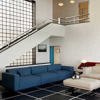 Modern blue sectional sofa on black and white checkered floor, with a minimalist beige armchair and bright wall accents.