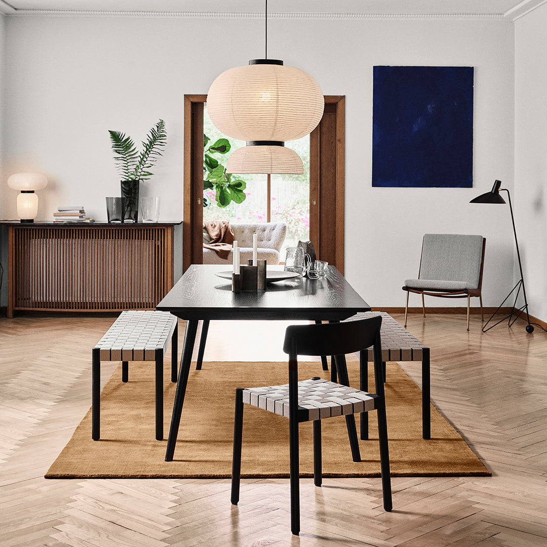 Modern dining room featuring black furniture, striped upholstery, and warm wood tones. Soft cream and blue accents throughout.