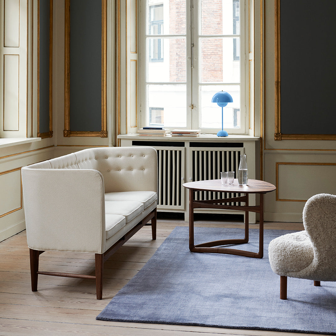 Elegant cream sofa, deep blue rug, and light wood accents in a stylish living room setting.
