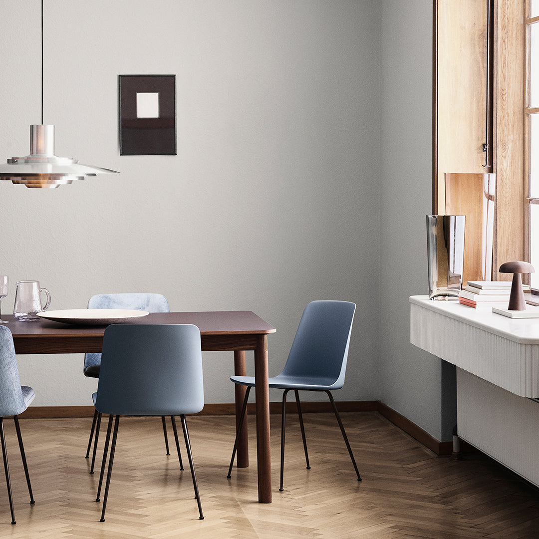 Modern dining room with light blue chairs and a dark wood table, featuring a chevron-patterned hardwood floor.