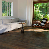 Modern living room featuring natural wood floor, white sofa, and black-and-white striped chair against lush greenery.