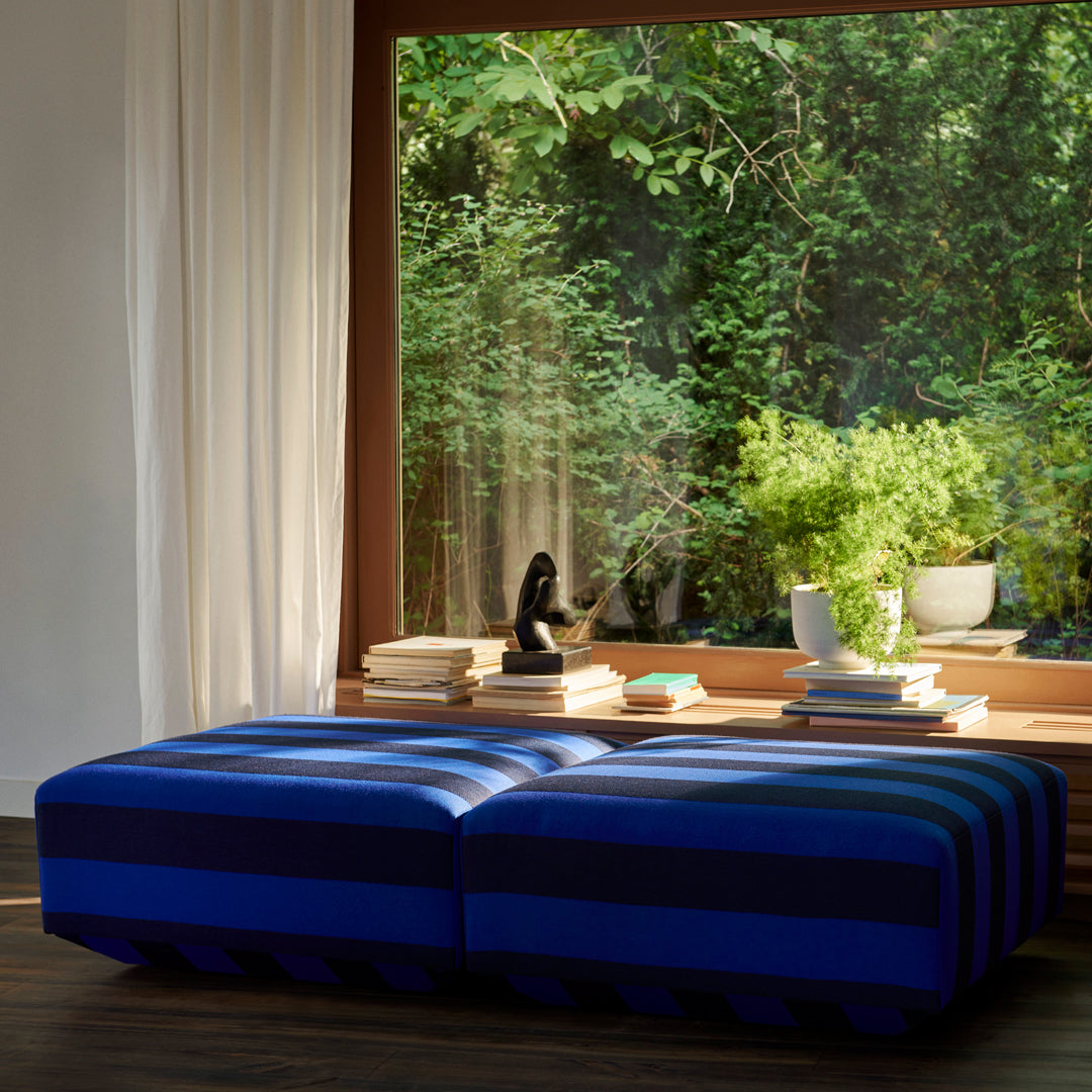 Blue striped ottoman with varying shades, adding a vibrant touch to modern interiors. 