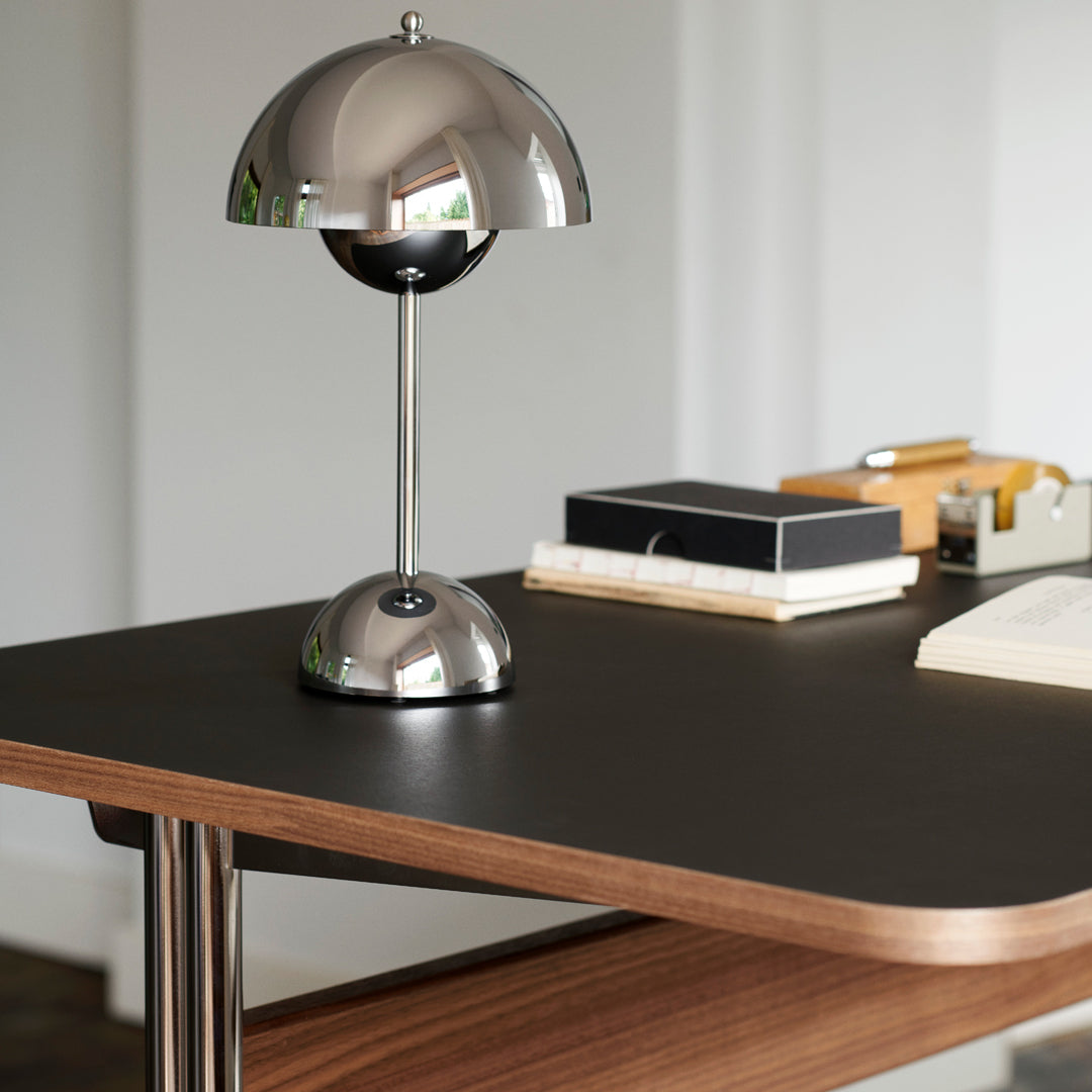 Modern chrome desk lamp with a round shade on a sleek walnut table, featuring clean lines and minimalist design.