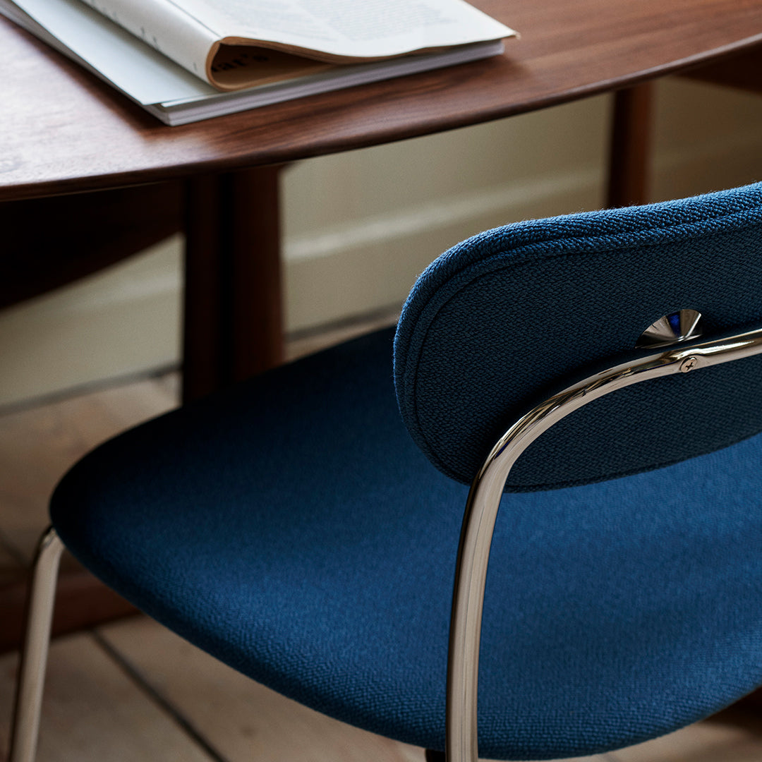 "Stylish blue upholstered chair with a sleek silver frame, paired with a wooden desk for a modern look."