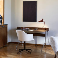 Modern wooden desk with a sleek black surface, paired with a white chair and warm wood flooring. Minimalist and elegant design.