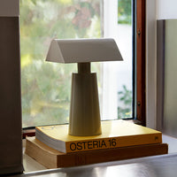 Modern white table lamp with a sleek geometric design on a yellow book. Minimalist aesthetic for home decor.