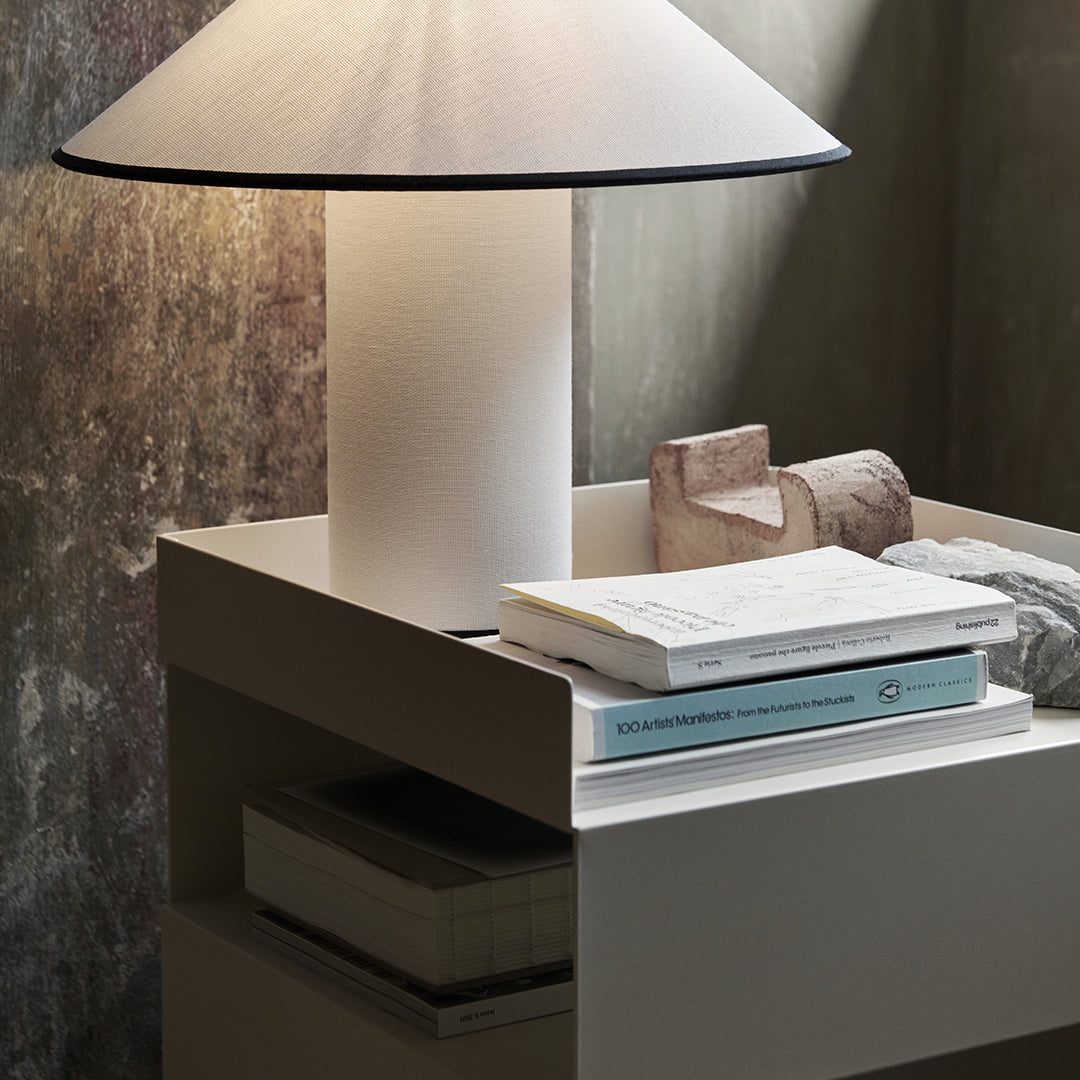 Modern white lamp on a minimalist nightstand, featuring soft textures and neutral tones with subtle earth colors.