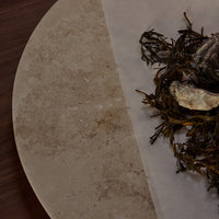 "Natural beige stone surface with earthy green seaweed accents and subtle texture contrasts."