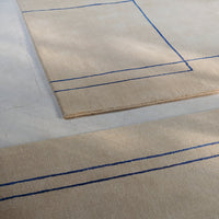 Beige rugs with blue geometric lines, stylishly arranged on a light surface to enhance modern decor.