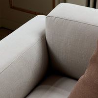 Light beige sofa upholstery with a textured fabric, featuring a contrasting brown pillow for added warmth.