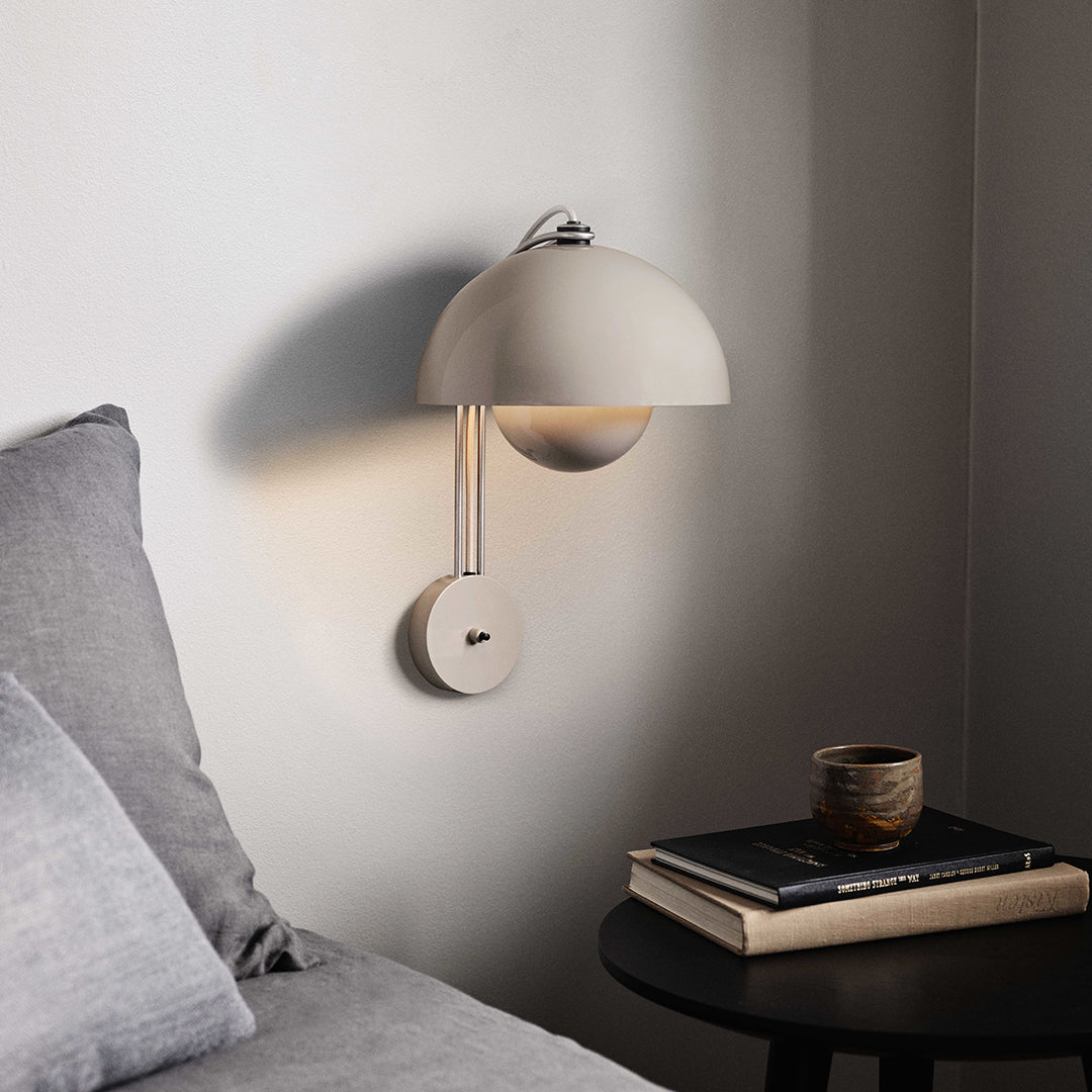 Modern beige wall lamp with a sleek dome shade, complementing soft gray bedding and a dark wooden side table.