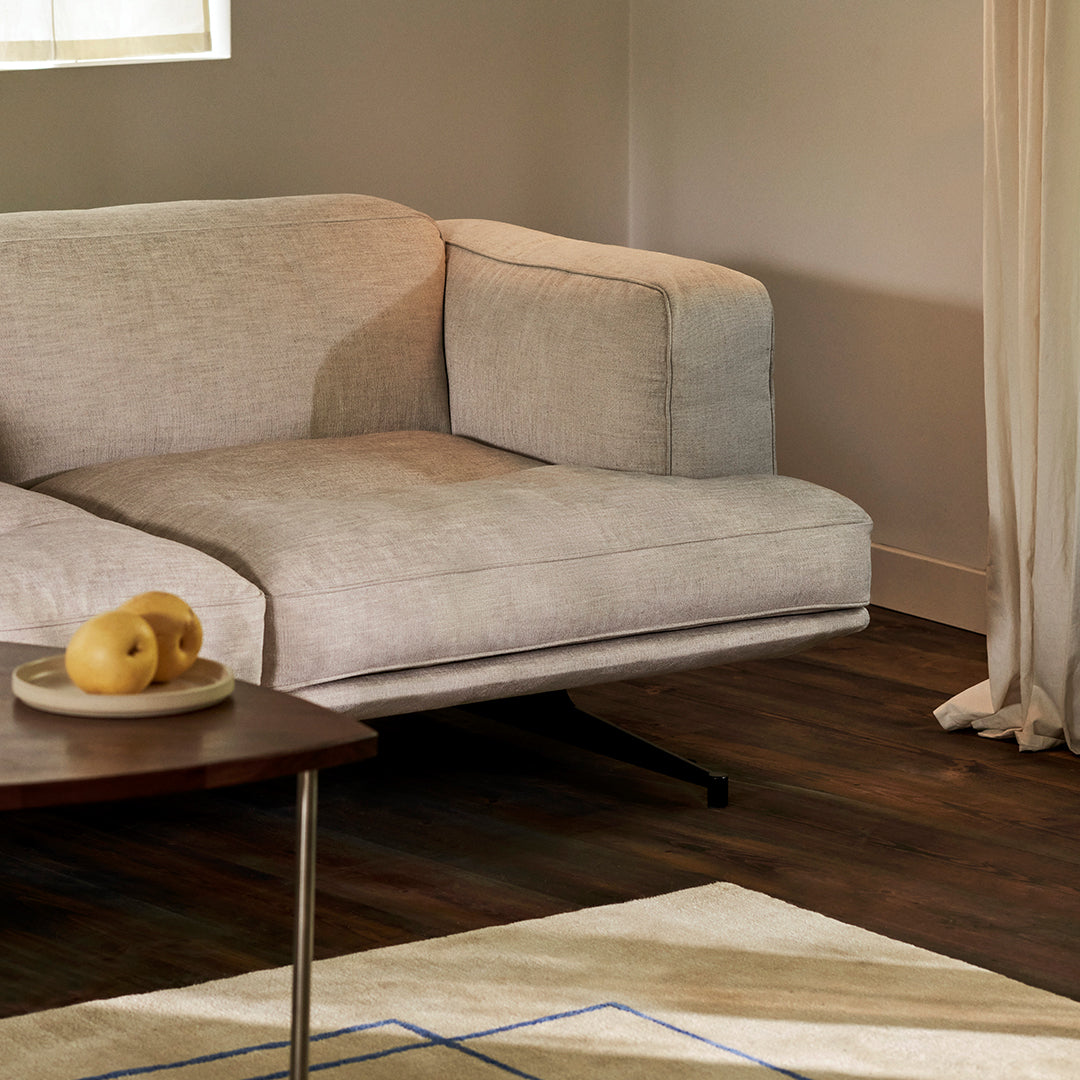 Light beige sectional sofa with subtle texture, accompanied by a cream and blue geometric patterned rug.