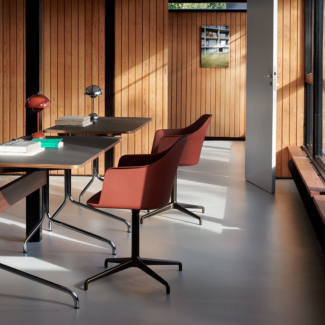 Modern workspace featuring rich wooden tones, sleek black accents, and deep burgundy chairs against a neutral floor.