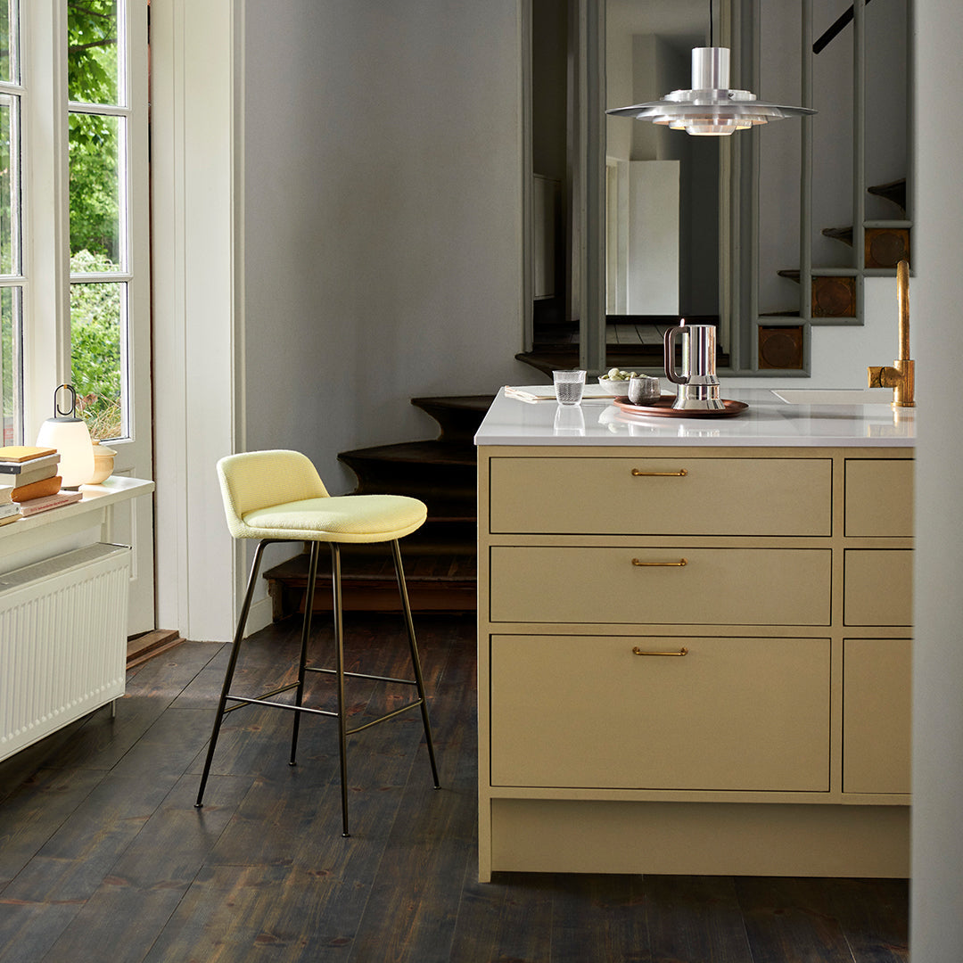 Light yellow bar stool in a beige kitchen with dark wood flooring and natural light from large windows.