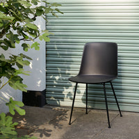 Matte black chair with smooth curves, set against a soft green background, perfect for modern decor.