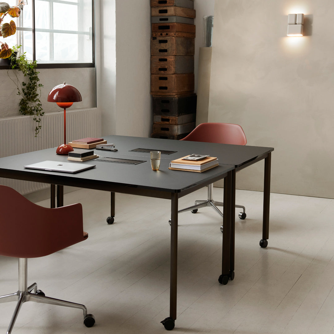 Black table with red chairs, warm lighting, and natural textures create a modern workspace atmosphere.