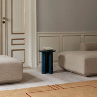 Beige textured furniture with a dark blue side table, featuring a minimalist design against a light gray wall.