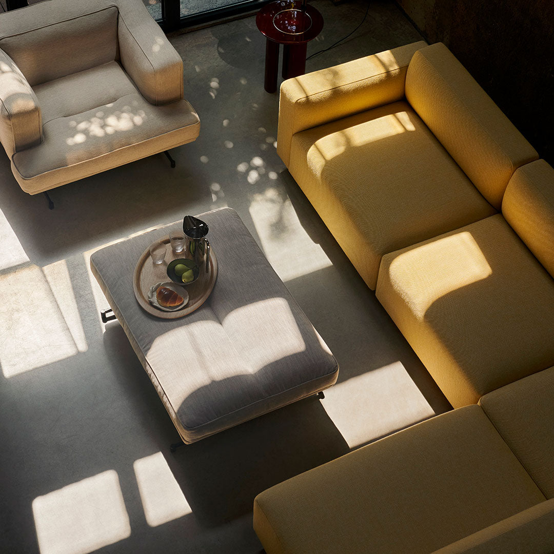 Stylish living room setting featuring yellow and neutral sofas with a light gray coffee table and scattered sunlight patterns.