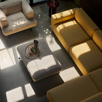 Stylish living room setting featuring yellow and neutral sofas with a light gray coffee table and scattered sunlight patterns.