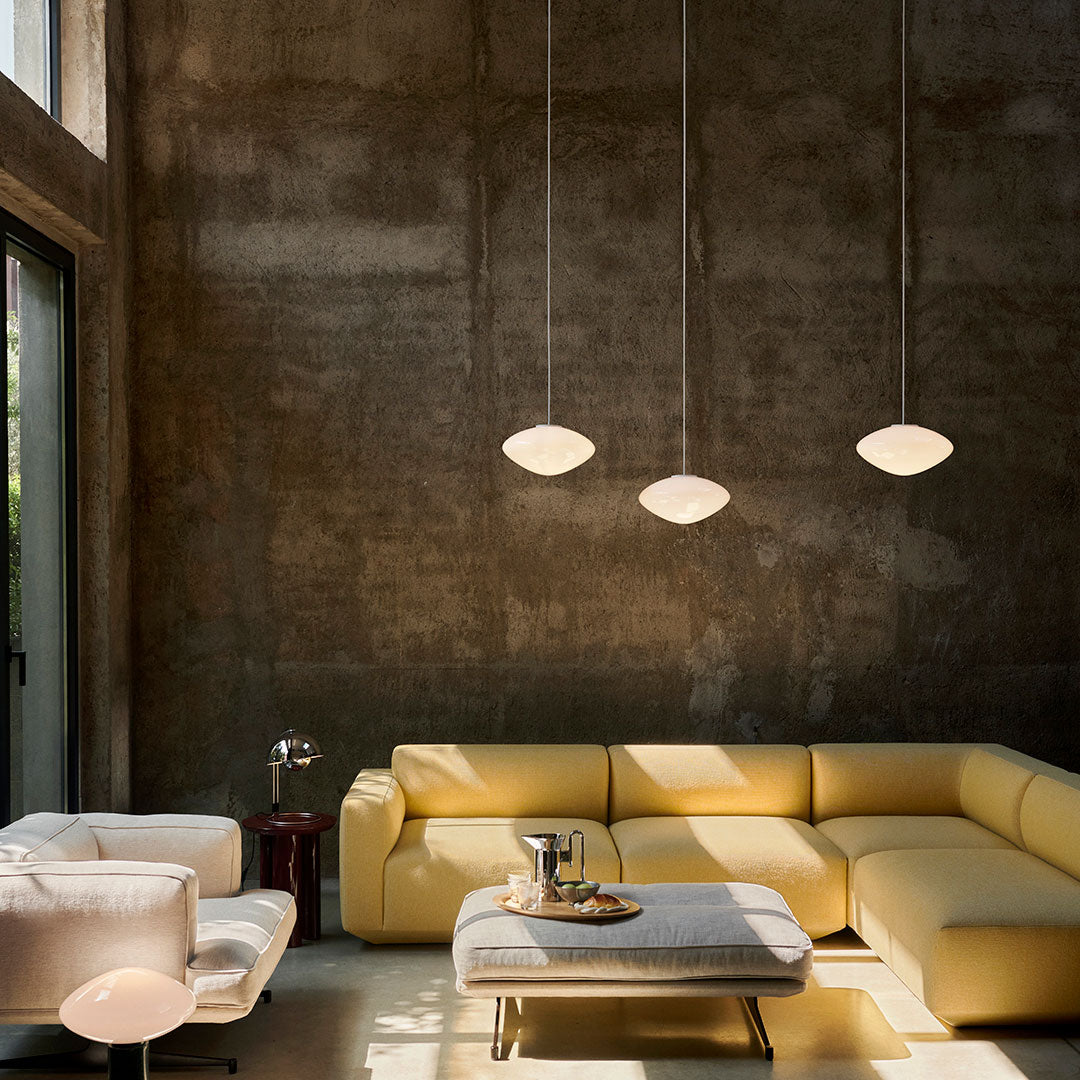 Modern living room featuring a yellow sectional sofa and white pendant lights against a textured gray wall.