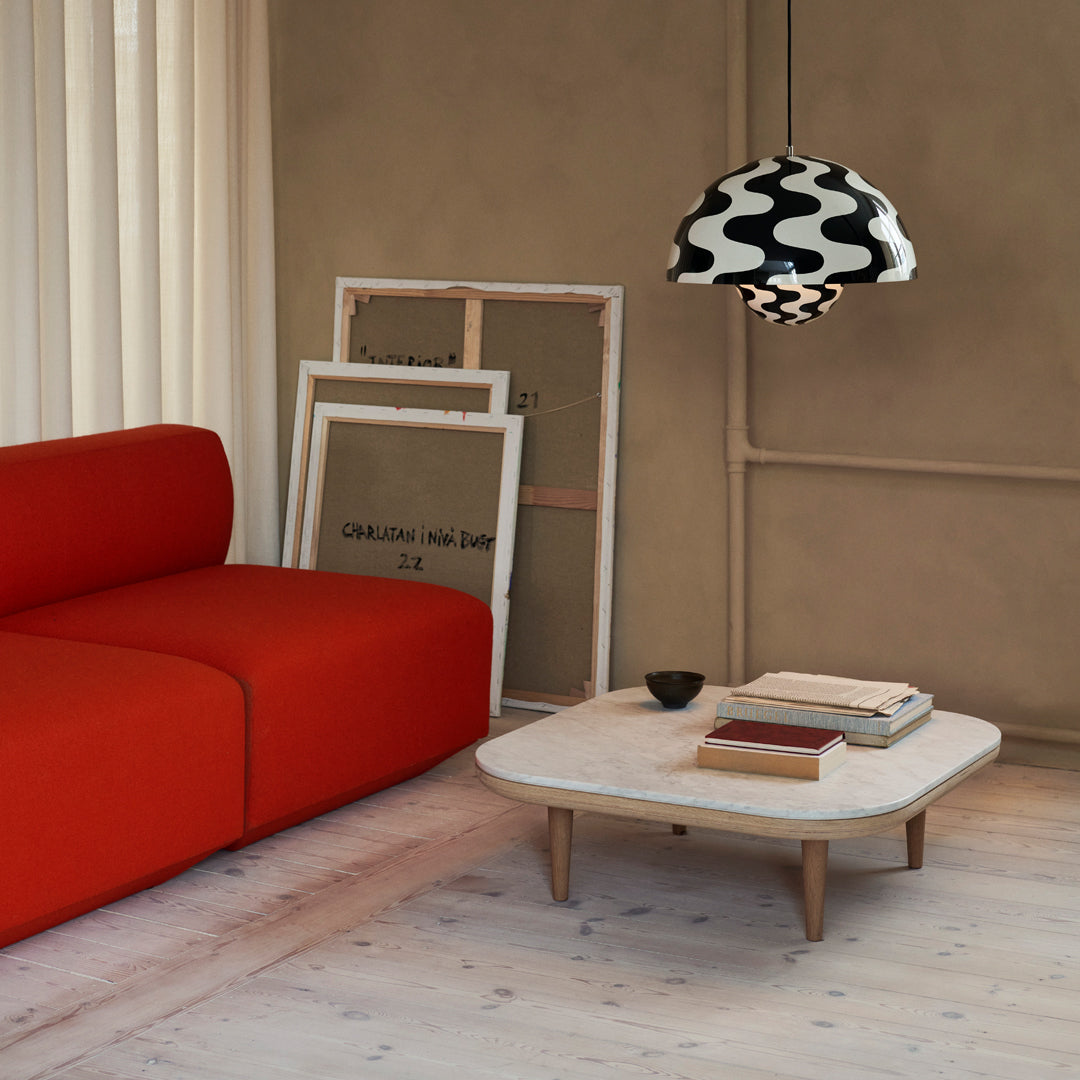 Vibrant red couch, sleek white coffee table, and bold black and white patterned lampshade against a soft beige backdrop.