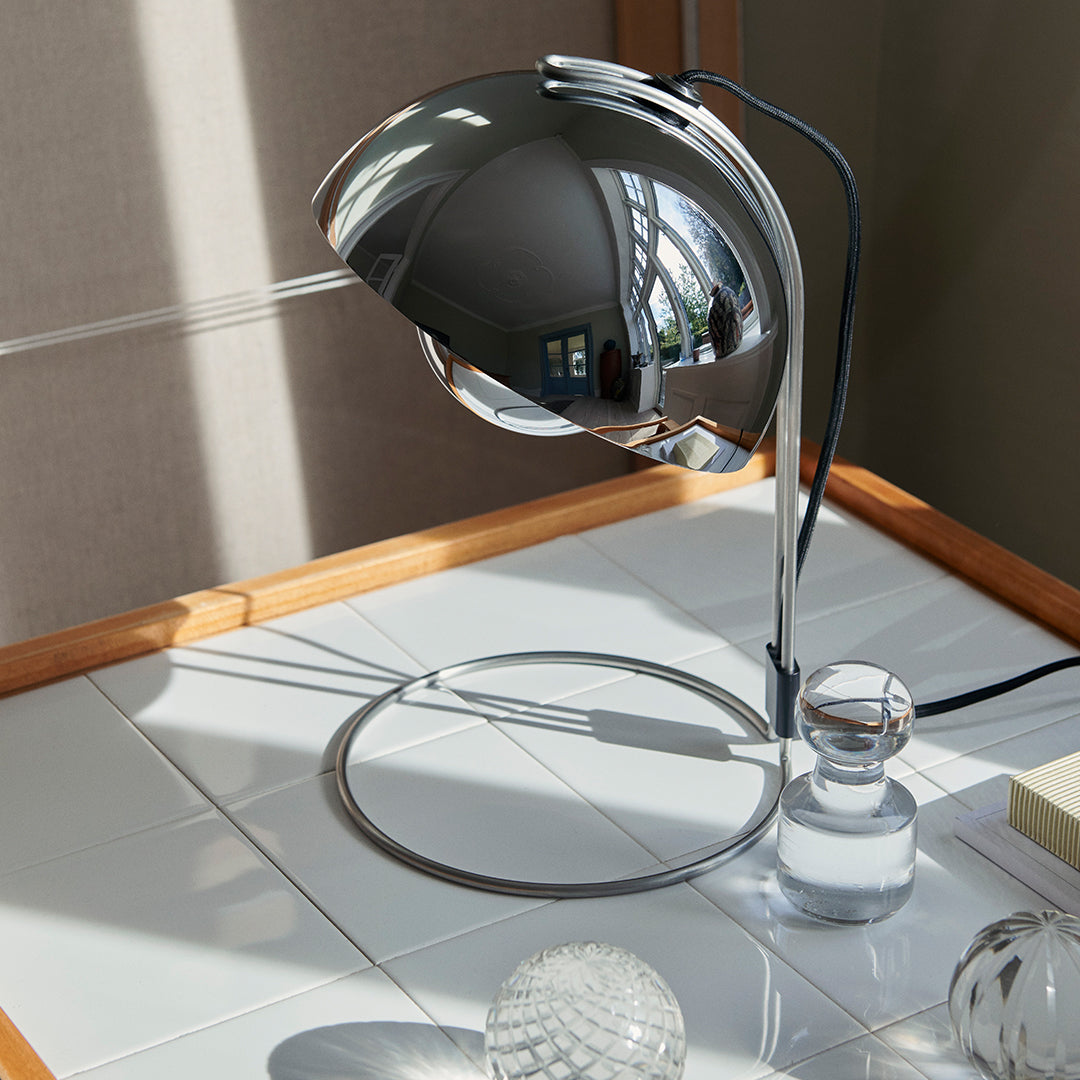 Modern chrome desk lamp with a sleek, reflective dome and minimalist design, set against a neutral background.