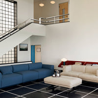 Modern living room featuring a blue sofa and cream-colored sectional, with geometric patterns on a black tiled floor.