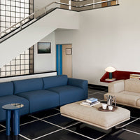 Modern living room with a blue sofa, tan armchair, and geometric black-and-white patterned flooring.