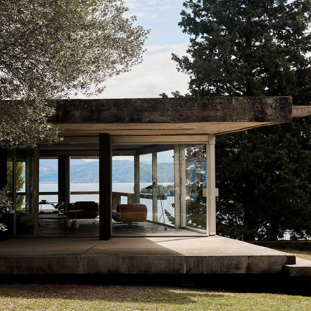 "Modern architecture in earthy tones with clean lines and large glass windows against a serene lake backdrop."