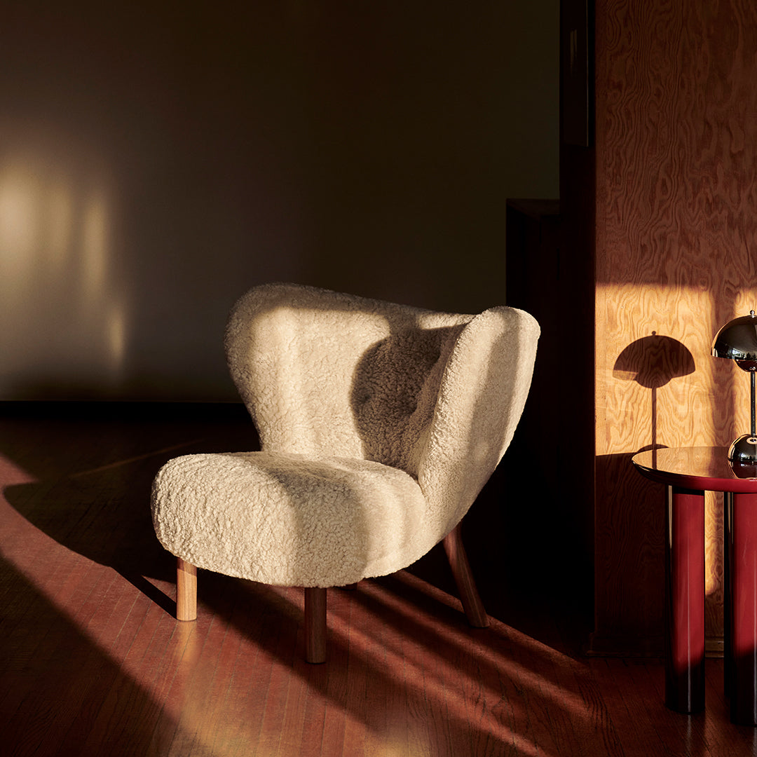 Cozy cream chair with a textured, fluffy pattern, set against warm wood tones and soft, golden lighting.
