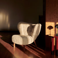 Cozy cream chair with a textured, fluffy pattern, set against warm wood tones and soft, golden lighting.