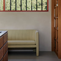 Light beige curved sofa with vertical ribbed pattern, set against a minimalist backdrop.