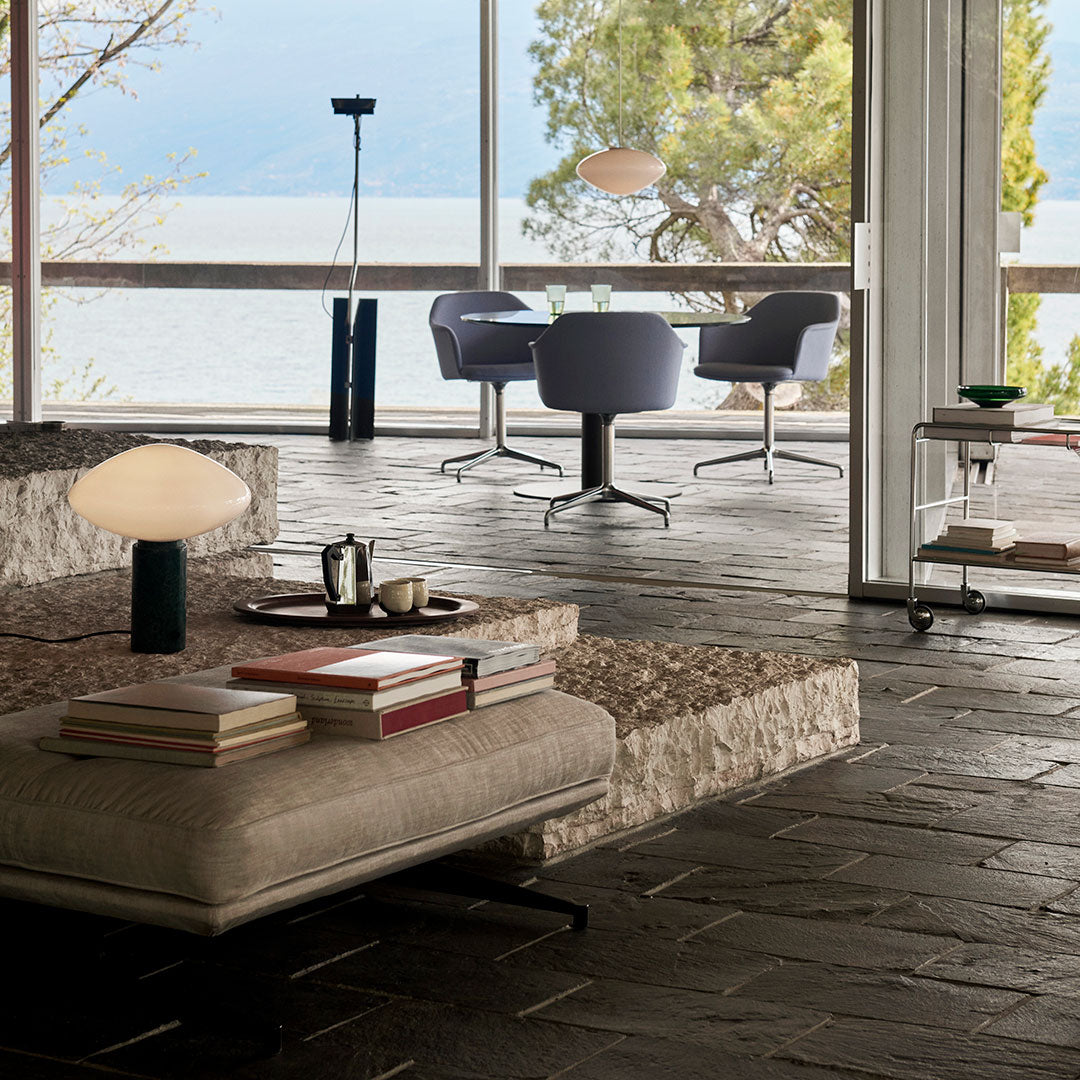 Modern living space featuring neutral tones, gray chairs, textured stone flooring, and warm lighting accents.