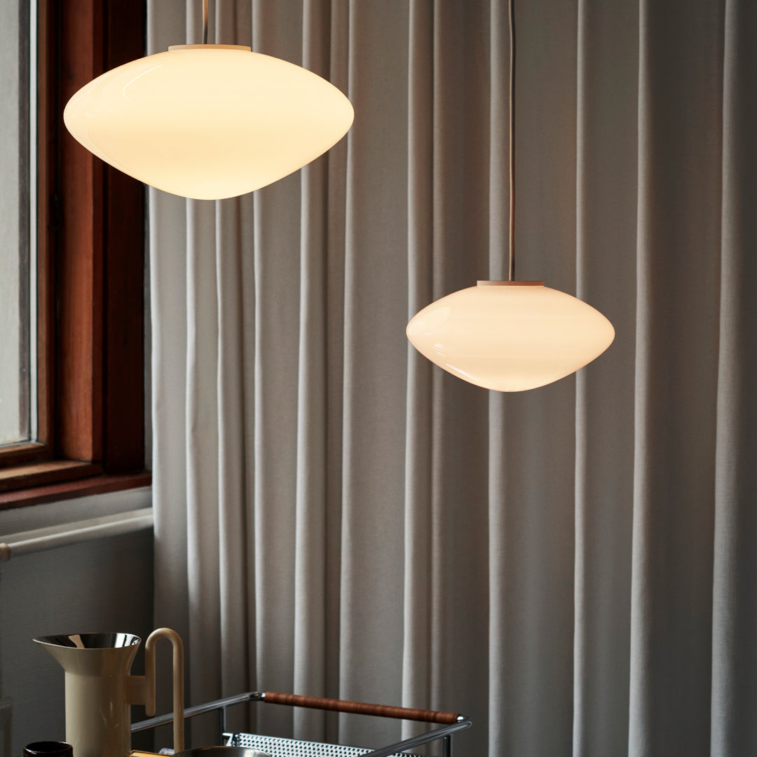 Cream pendant lights with smooth, rounded shapes hanging against a soft gray backdrop. Elegant and minimalistic design.